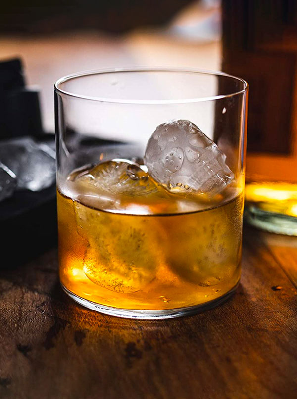Glass filled with tea holding four skull ice cubes.