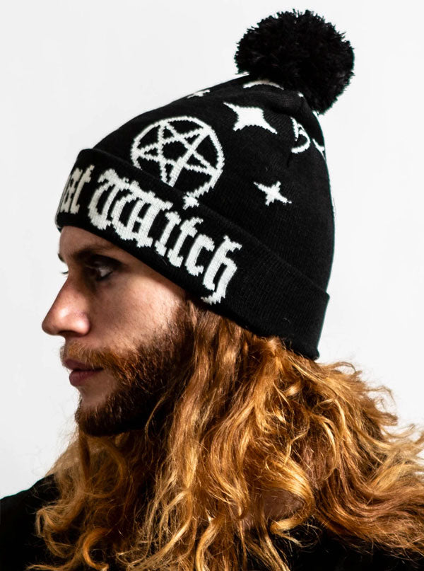 The left side of a mans face modeling a black beanie with text that reads &quot;100% that witch&quot; with a black pom pom on top